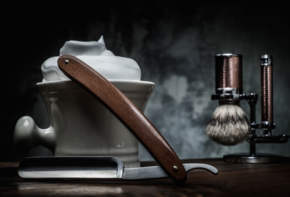 barbers tools with shaving cream on dark background