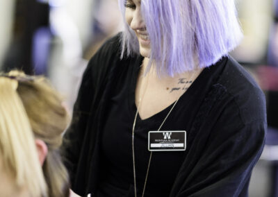 A woman in violet hair making hairstyling to client