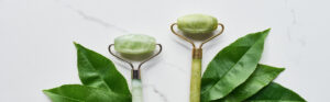 panoramic shot of jadeite face rollers with plant leaves on marb